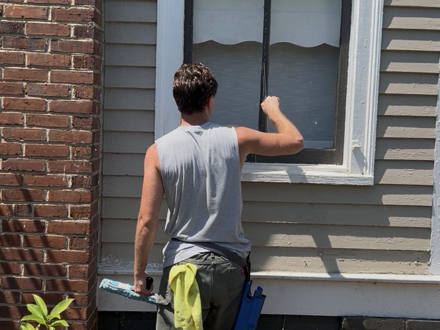Technician hand-detailing an exterior window frame