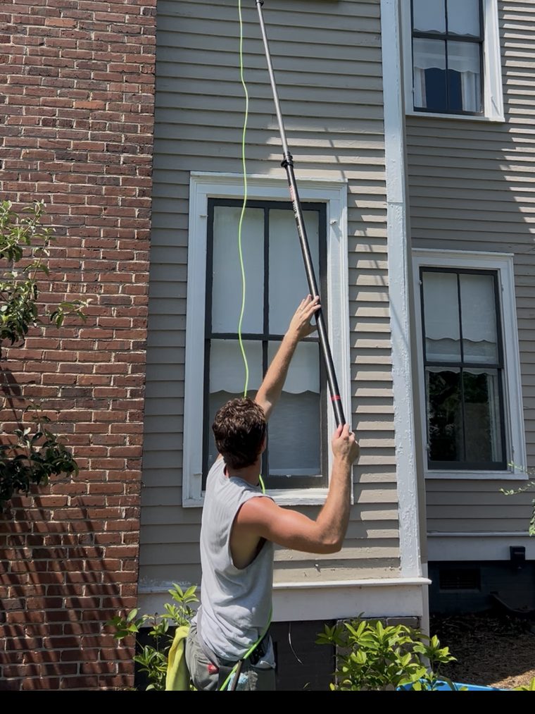 Second-story window being washed with a water-fed extension pole