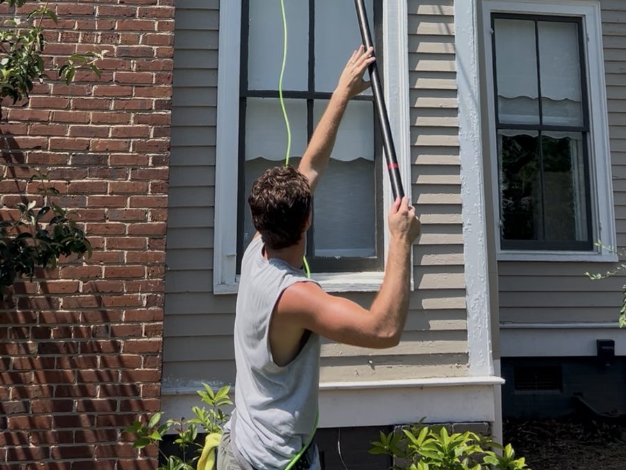 Technician washing a second-story window with an extension pole
